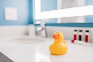 a rubber ducky sits on a hotel room bathroom