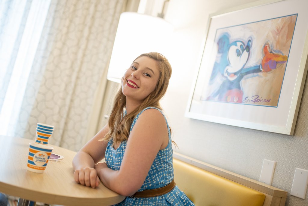 a woman dressed in a retro look sits at a table inside a hotel room