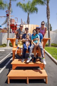 a family sits on the large orange Adirondack chair at Howard Johnson Anaheim