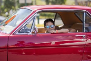a child sits in the front seat of a retro red car and smiles