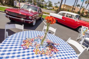 candy and flowers pictured on a table at the Howard Johnson Anaheim retro unveiling event near retro cars