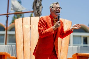 pop culture historian Charles Phoenix holds a microphone atop the large orange Adirondack chair at Howard Johnson Anaheim