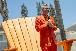 pop culture historian Charles Phoenix holds a microphone atop the large orange Adirondack chair at Howard Johnson Anaheim