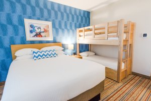 Mickey Mouse themed hotel room with a bed and bunk bed set
