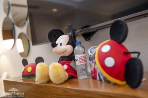 Mickey Mouse themed accessories, items, and a cake sit on a table in a hotel room