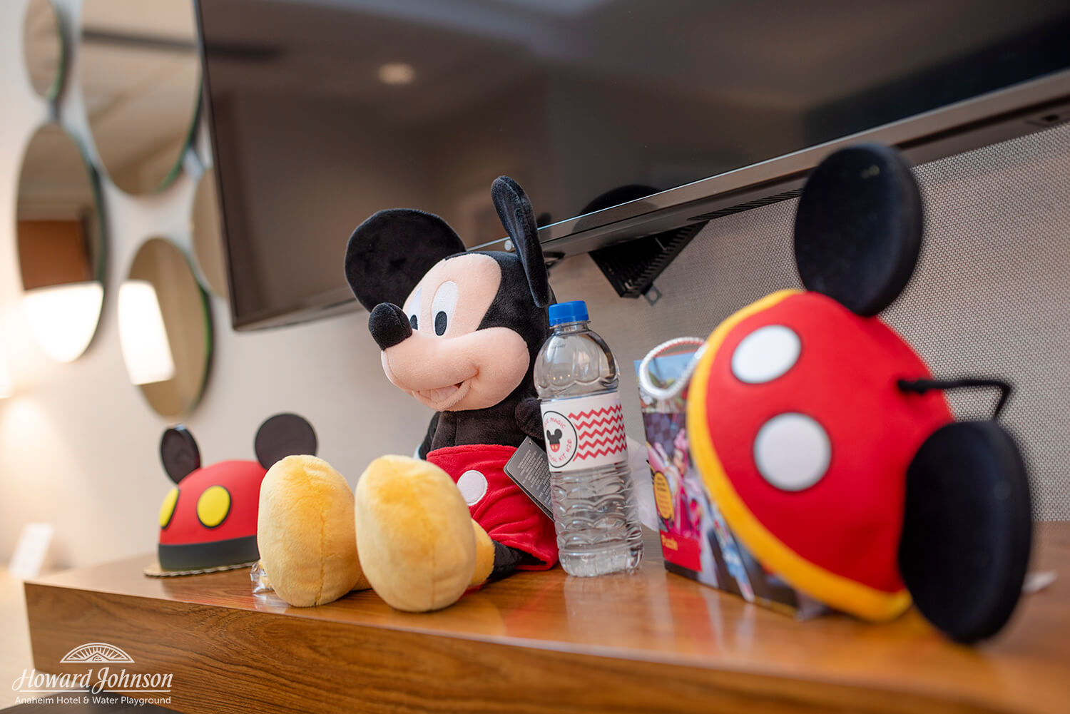 Mickey Mouse themed accessories, items, and a cake sit on a table in a hotel room