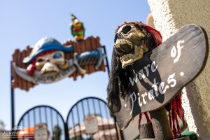 A closeup of skull and pirate decor, including a 'Beware of Pirates' sign and the Castaway Cove water playground sign at Howard Johnson Anaheim