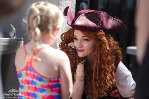 a woman dressed as a pirate smiles at a little girl