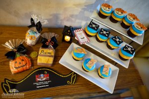 a collection of pirate and halloween themed cookies and cupcakes lay on a table
