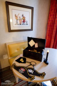 pirate themed accessories, including a hat, keys, candle, and treasure chest, lay on a table in a hotel room