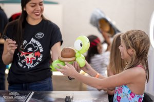 a woman holds an inflatable balloon turtle out to a little girl