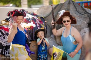 two women and a little boy pose with toy guns and pirate hats for a photo