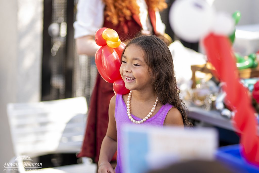 a little girl with an inflatable parrot on her shoulder smiles