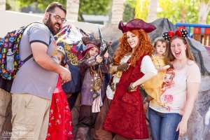 a family dressed in Disney gear poses with a woman dressed in a pirate costume