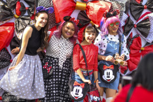 a group of young women pose for a photo wearing polka dots in front of a backdrop of polka dot bows