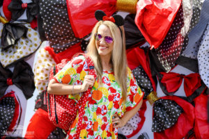 a woman poses for a picture while holding a polka dot backpack in front of a backdrop of polka dot bows