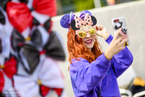 a young woman takes a selfie with Minnie Mouse sunglasses
