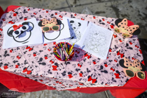 Minnie Mouse coloring pages, sunglasses, and crayons are pictured on a Minnie themed craft table