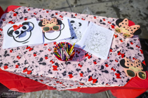 Minnie Mouse coloring pages, sunglasses, and crayons are pictured on a Minnie themed craft table