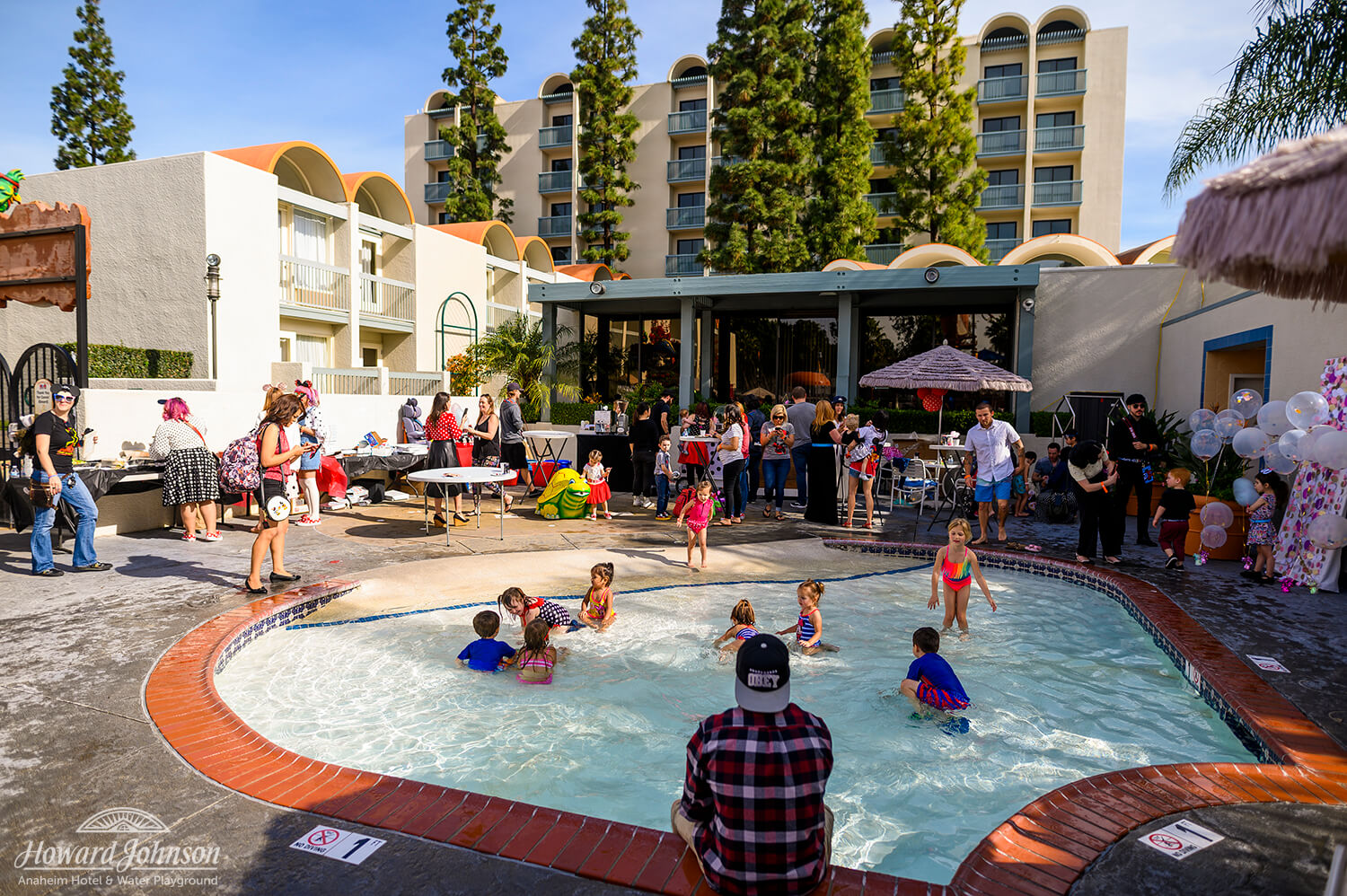 Children and parents gather around and play in the shallow pool at Howard Johnson Anaheim hotel