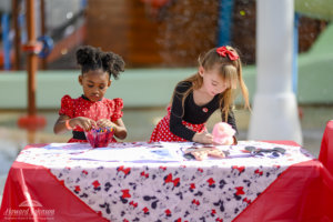Two young girls color with crayons on a Minnie Mouse craft table