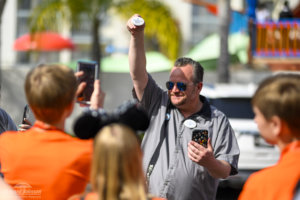 A man holds a nametag in the air as he leads a group of people