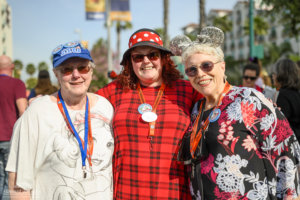 Three women wearing Disney hats and lanyards smile for the camera