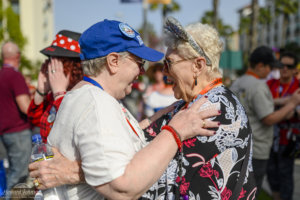 Two women wearing disney hats embrace in a hug and smile