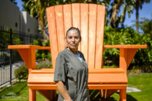 A Howard Johnson Anaheim employee named Teresa poses outside the hotel in front of a large orange Adirondack chair