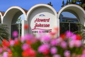 A close up of the Howard Johnson Anaheim hotel with pink flowers blurred in the foreground