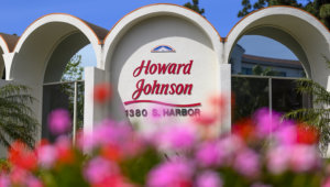 A close up of the Howard Johnson Anaheim hotel with pink flowers blurred in the foreground