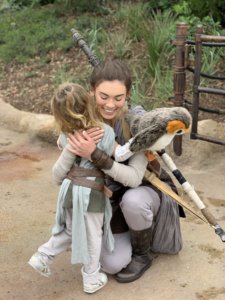 A little girl hugs a woman dressed as the character Rey from Star Wars