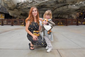 A woman and a little girl pose for a picture in front of a theme park